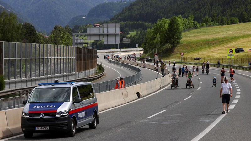 Sebuah kendaraan polisi berjaga-jaga, sementara orang-orang berdemonstrasi menentang peningkatan kepadatan lalu lintas di jalan tol Brenner antara Austria dan Italia, dekat Matrei, Austria, Sabtu (30/5/2026). (REUTERS/Christian Mang)