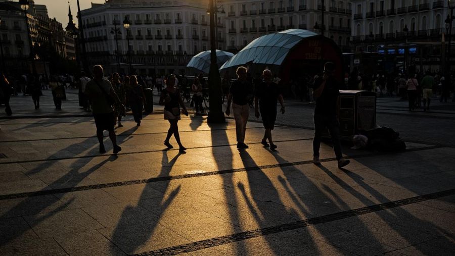 Orang-orang berjalan dan membentuk bayangan panjang saat matahari terbenam di Puerta del Sol selama gelombang panas musim semi di Madrid, Spanyol, 30 Mei 2026. (REUTERS/Kacper Pempel)