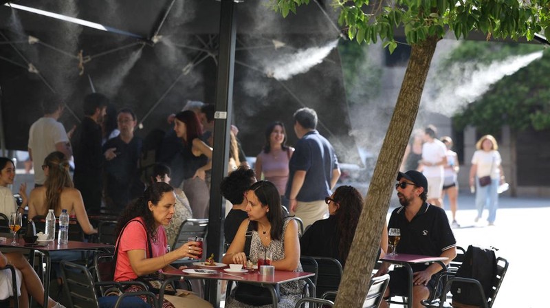 Orang-orang duduk dan berbincang di bar dengan sistem pengkabutan untuk mendinginkan pelanggan, selama gelombang panas musim semi di Madrid, Spanyol, 29 Mei 2026.