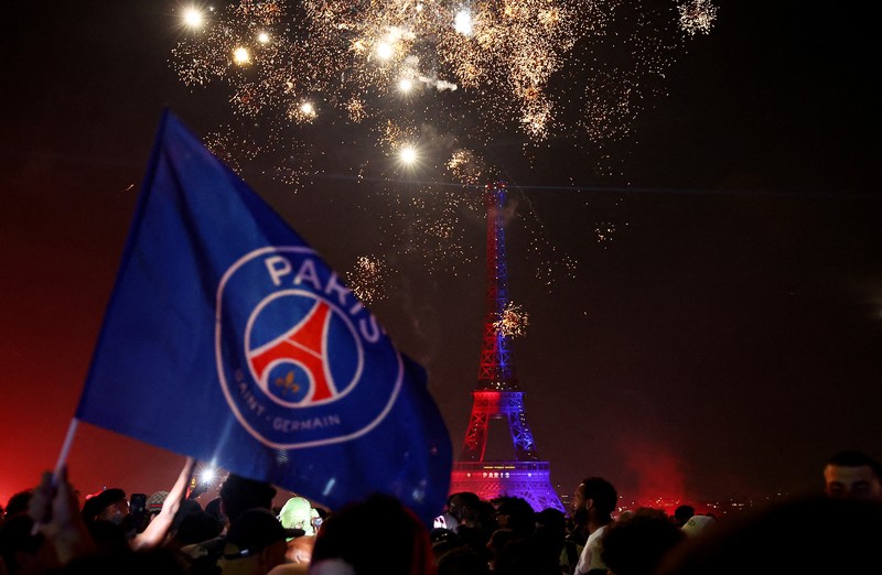 Petugas kepolisian berlindung dari suar yang dinyalakan massa saat perayaan kemenangan Paris Saint-Germain usai menjuarai Liga Champions UEFA di Paris, Minggu (31/5/2026). (REUTERS/Abdul Saboor)