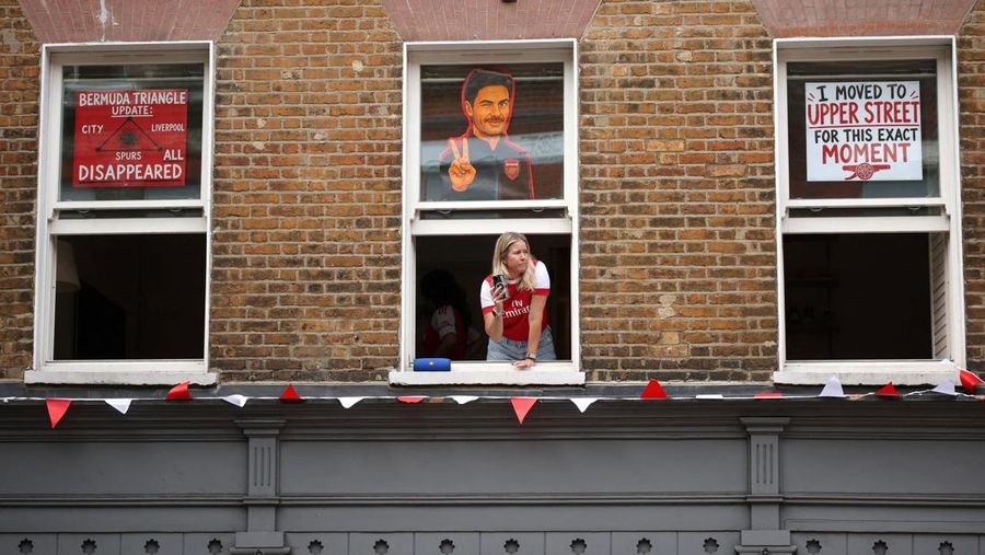 Pemandangan umum seorang penggemar Arsenal terlihat dari jendela saat para pendukung berkumpul menjelang parade kemenangan Premier League di London, Minggu (31/5/2026).