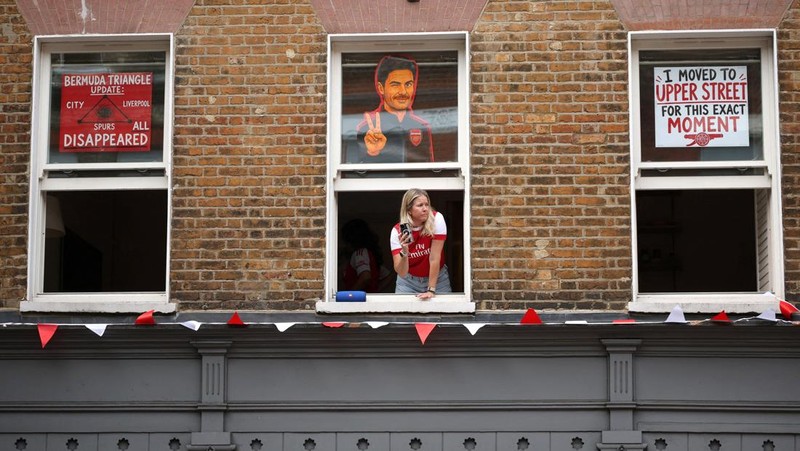 Pemandangan umum seorang penggemar Arsenal terlihat dari jendela saat para pendukung berkumpul menjelang parade kemenangan Premier League di London, Minggu (31/5/2026).
