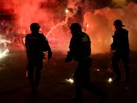 Petugas kepolisian berlindung dari suar yang dinyalakan massa saat perayaan kemenangan Paris Saint-Germain usai menjuarai Liga Champions UEFA di Paris, Minggu (31/5/2026). (REUTERS/Abdul Saboor)