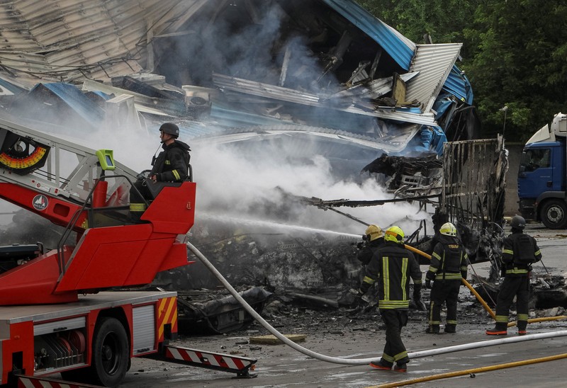 Petugas pemadam kebakaran dan jurnalis bekerja di lokasi serangan pesawat tak berawak Rusia, di tengah serangan Rusia terhadap Ukraina, di Dnipro, Ukraina, 31 Mei 2026. (REUTERS/Stringer)