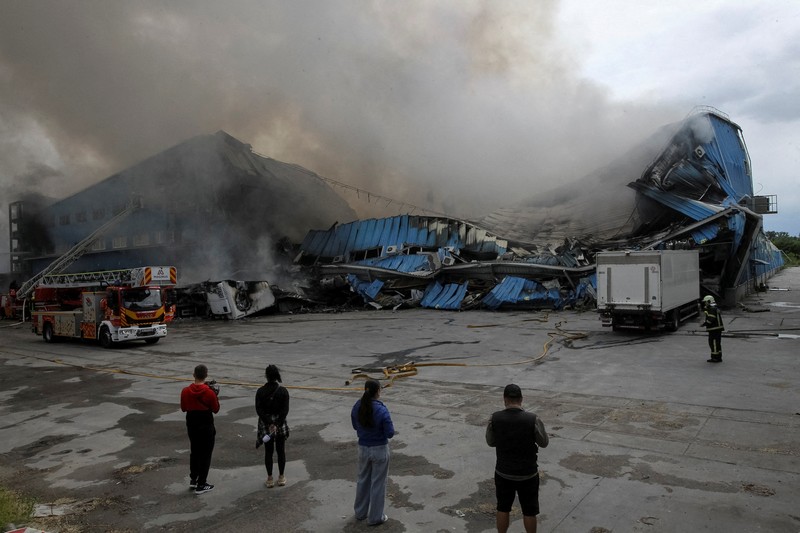 Petugas pemadam kebakaran dan jurnalis bekerja di lokasi serangan pesawat tak berawak Rusia, di tengah serangan Rusia terhadap Ukraina, di Dnipro, Ukraina, 31 Mei 2026. (REUTERS/Stringer)