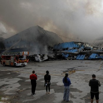 Petugas pemadam kebakaran dan jurnalis bekerja di lokasi serangan pesawat tak berawak Rusia, di tengah serangan Rusia terhadap Ukraina, di Dnipro, Ukraina, 31 Mei 2026. (REUTERS/Stringer)