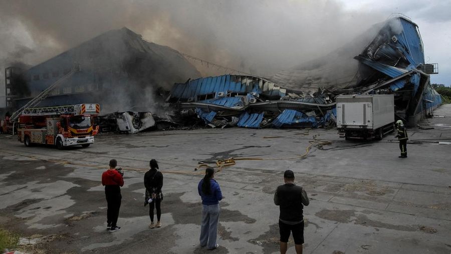 Petugas pemadam kebakaran dan jurnalis bekerja di lokasi serangan pesawat tak berawak Rusia, di tengah serangan Rusia terhadap Ukraina, di Dnipro, Ukraina, 31 Mei 2026. (REUTERS/Stringer)