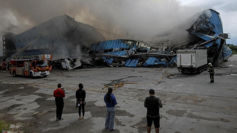 Petugas pemadam kebakaran dan jurnalis bekerja di lokasi serangan pesawat tak berawak Rusia, di tengah serangan Rusia terhadap Ukraina, di Dnipro, Ukraina, 31 Mei 2026. (REUTERS/Stringer)