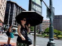 Seorang wanita dengan payung berjalan melewati panel suhu yang menunjukkan angka 42 derajat Celcius selama gelombang panas musim semi di Bilbao, Spanyol, 27 Mei 2026. (REUTERS/Vincent West)