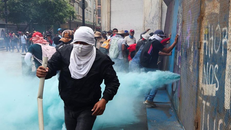 Para demonstran mendorong barikade logam saat para guru dari serikat Koordinasi Nasional Pekerja Pendidikan Meksiko (CNTE) berunjuk rasa menuntut upah dan pensiun yang lebih baik, dengan slogan