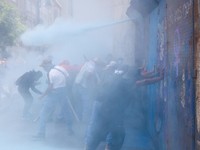 Para demonstran mendorong barikade logam sementara mereka dibubarkan dengan gas air mata saat para guru dari serikat Koordinasi Nasional Pekerja Pendidikan Meksiko (CNTE) berunjuk rasa menuntut upah dan pensiun yang lebih baik, dengan slogan "Jika ti