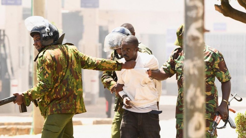 Petugas polisi anti huru hara menahan seorang demonstran selama protes menentang rencana karantina Ebola yang didukung AS terkait pembangunan fasilitas berkapasitas 50 tempat tidur di pangkalan angkatan udara Kenya yang dimaksudkan untuk menampung warga Amerika yang terpapar Ebola, di kota Nanyuki, Kabupaten Laikipia, Kenya, 1 Juni 2026.