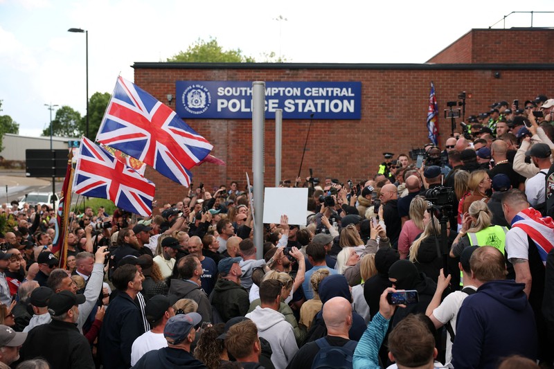 Para pengunjuk rasa berdiri menghadap petugas polisi selama demonstrasi menyusul vonis terhadap Vikrum Digwa atas pembunuhan mahasiswa Henry Nowak, di Southampton, Inggris, 2 Juni 2026. (REUTERS/Isabel Infantes)