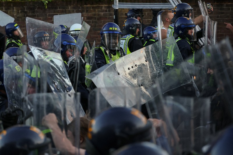Para pengunjuk rasa berdiri menghadap petugas polisi selama demonstrasi menyusul vonis terhadap Vikrum Digwa atas pembunuhan mahasiswa Henry Nowak, di Southampton, Inggris, 2 Juni 2026. (REUTERS/Isabel Infantes)