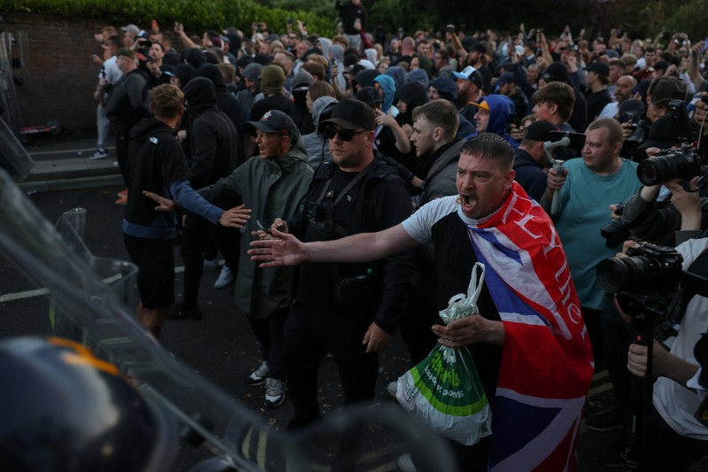 Para pengunjuk rasa berdiri menghadap petugas polisi selama demonstrasi menyusul vonis terhadap Vikrum Digwa atas pembunuhan mahasiswa Henry Nowak, di Southampton, Inggris, 2 Juni 2026. (REUTERS/Isabel Infantes)