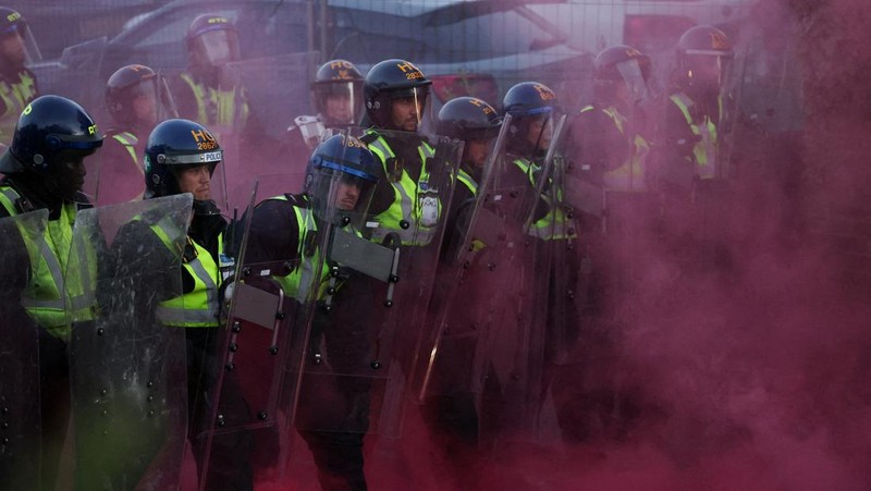 Para petugas polisi berjaga di tengah asap berwarna selama demonstrasi menyusul vonis terhadap Vikrum Digwa atas pembunuhan mahasiswa Henry Nowak, di Southampton, Inggris, 2 Juni 2026.