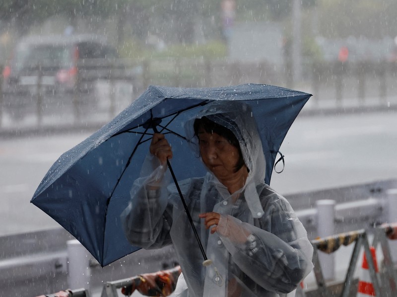 Seorang turis yang mengenakan jas hujan berjalan menerobos hujan deras akibat Topan Jangmi di Tokyo, Jepang, 3 Juni 2026. (REUTERS/Kim Kyung-Hoon)