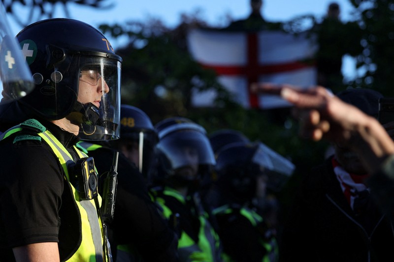 Para pengunjuk rasa berdiri menghadap petugas polisi selama demonstrasi menyusul vonis terhadap Vikrum Digwa atas pembunuhan mahasiswa Henry Nowak, di Southampton, Inggris, 2 Juni 2026. (REUTERS/Isabel Infantes)