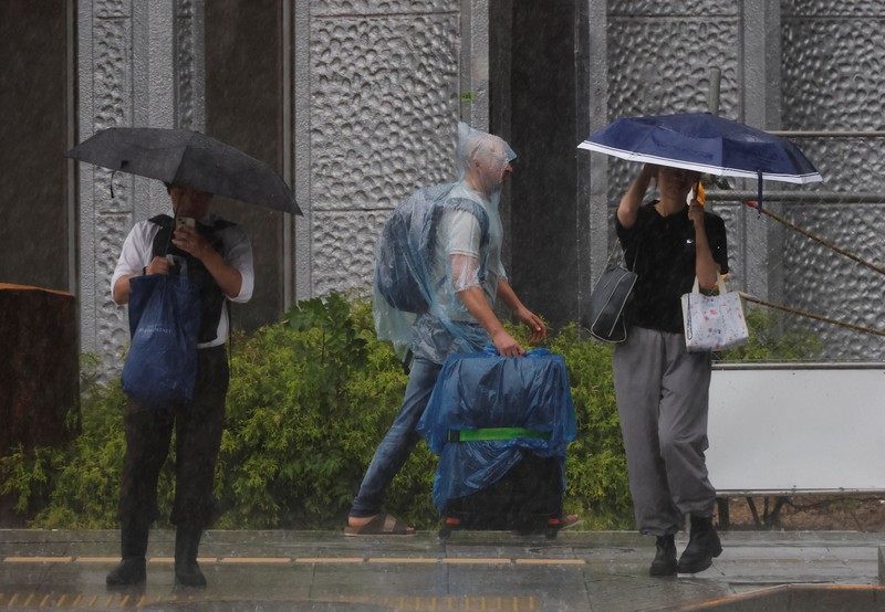 Seorang turis yang mengenakan jas hujan berjalan menerobos hujan deras akibat Topan Jangmi di Tokyo, Jepang, 3 Juni 2026. (REUTERS/Kim Kyung-Hoon)