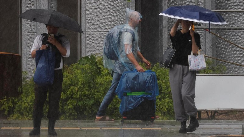 Seorang turis yang mengenakan jas hujan berjalan menerobos hujan deras akibat Topan Jangmi di Tokyo, Jepang, 3 Juni 2026. (REUTERS/Kim Kyung-Hoon)