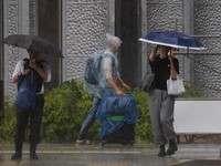 Seorang turis yang mengenakan jas hujan berjalan menerobos hujan deras akibat Topan Jangmi di Tokyo, Jepang, 3 Juni 2026. (REUTERS/Kim Kyung-Hoon)