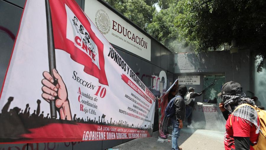 Para pembimbing pembangkang dari Koordinasi Nasional Pekerja Pendidikan Meksiko (CNTE) merusak salah satu titik akses ke instansi Sekretariat Pendidikan Publik (SEP) selama protes untuk menuntut bayaran dan pensiun nan lebih baik, dengan slogan