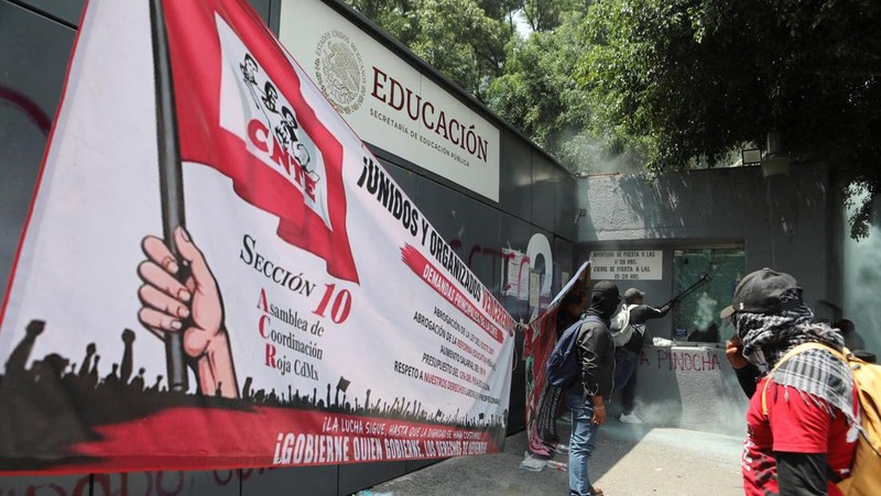 Para guru pembangkang dari Koordinasi Nasional Pekerja Pendidikan Meksiko (CNTE) merusak salah satu titik akses ke kantor Sekretariat Pendidikan Publik (SEP) selama protes untuk menuntut upah dan pensiun yang lebih baik, dengan slogan