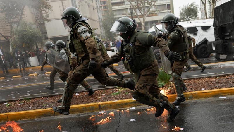Petugas polisi anti huru hara berlari melewati kobaran api dari bom molotov selama protes terhadap kebijakan pemerintah Presiden Chili Jose Antonio Kast, di Santiago, Chili, 3 Juni 2026.