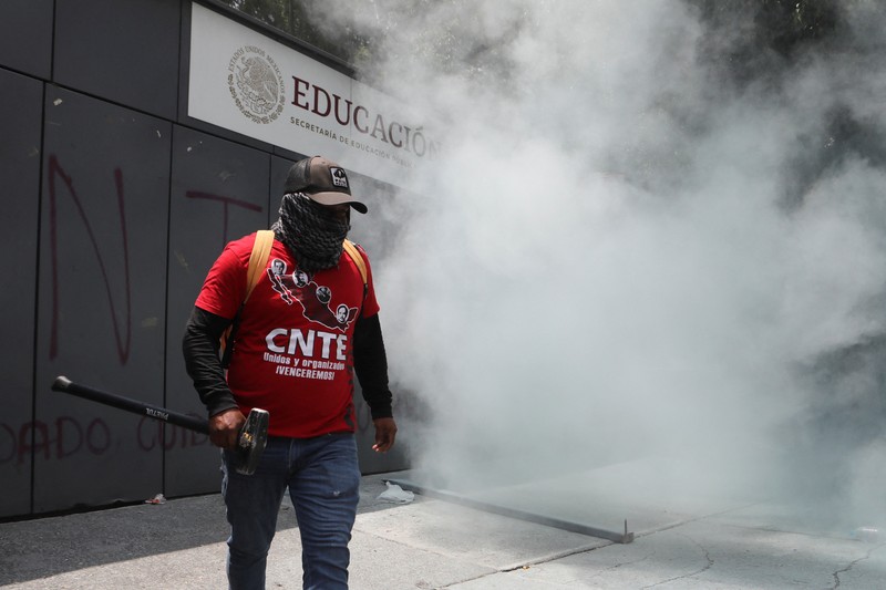 Para guru pembangkang dari Koordinasi Nasional Pekerja Pendidikan Meksiko (CNTE) berkumpul di luar salah satu titik akses ke kantor Sekretariat Pendidikan Publik (SEP) selama protes untuk menuntut upah dan pensiun yang lebih baik, dengan slogan