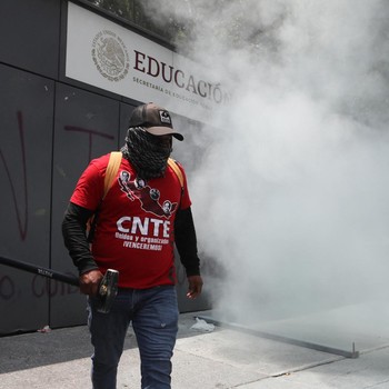 Seorang guru pembangkang dari Koordinasi Nasional Pekerja Pendidikan Meksiko (CNTE) berdiri di tengah gas air mata di luar kantor Sekretariat Pendidikan Publik (SEP) selama protes untuk menuntut upah dan pensiun yang lebih baik, dengan slogan "Jika t
