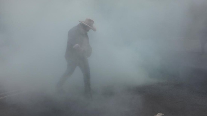 Seorang guru pembangkang dari Koordinasi Nasional Pekerja Pendidikan Meksiko (CNTE) berjalan di tengah gas air mata di luar Sekretariat Pendidikan Publik (SEP) selama protes untuk menuntut upah dan pensiun yang lebih baik, dengan slogan