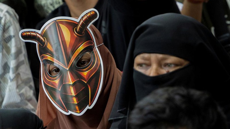 A girl wears a cockroach themed mask, as supporters of the Cockroach Janta Party (CJP) listens to Abhijeet Dipke, head of the CJP, during a sit-in protest demanding the resignation of Indian Education Minister Dharmendra Pradhan, in New Delhi, India,
