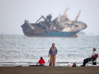 Warga beraktivitas di pesisir Bandar Abbas, Iran, sementara sebuah kapal terlihat melintas di Selat Hormuz, Sabtu (31/5/2026). Jalur pelayaran strategis ini menjadi salah satu urat nadi perdagangan energi dunia karena dilalui sebagian besar ekspor mi