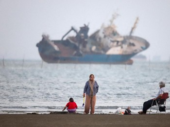 Warga beraktivitas di pesisir Bandar Abbas, Iran, sementara sebuah kapal terlihat melintas di Selat Hormuz, Sabtu (31/5/2026). Jalur pelayaran strategis ini menjadi salah satu urat nadi perdagangan energi dunia karena dilalui sebagian besar ekspor mi