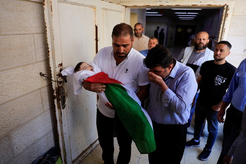 Ayah dan saudara laki-laki Sam Abu Haykal, seorang bayi Palestina berusia 7 bulan yang dibunuh oleh tentara Israel, membawa jenazahnya selama pemakamannya di Hebron di Tepi Barat yang diduduki Israel, 6 Juni 2026. REUTERS/Mussa Qawasma