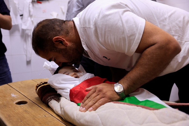 Ayah dan saudara laki-laki Sam Abu Haykal, seorang bayi Palestina berusia 7 bulan yang dibunuh oleh tentara Israel, membawa jenazahnya selama pemakamannya di Hebron di Tepi Barat yang diduduki Israel, 6 Juni 2026. REUTERS/Mussa Qawasma