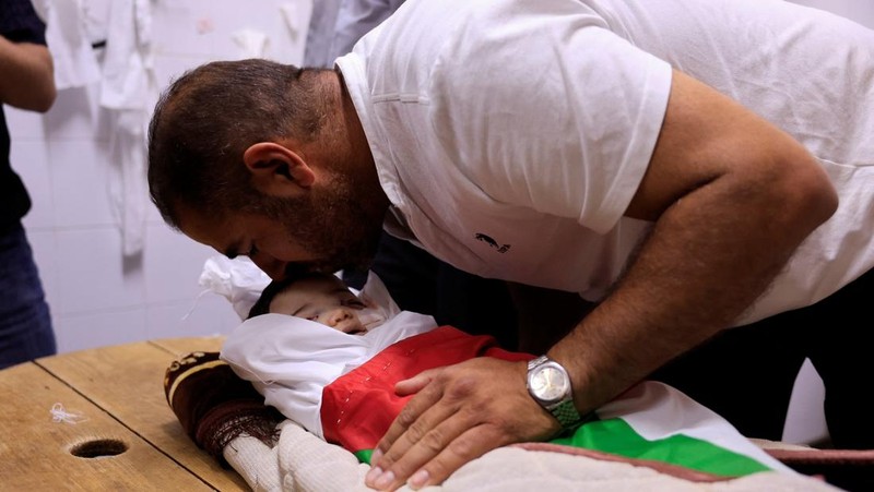 Ayah dan saudara laki-laki Sam Abu Haykal, seorang bayi Palestina berusia 7 bulan yang dibunuh oleh tentara Israel, membawa jenazahnya selama pemakamannya di Hebron di Tepi Barat yang diduduki Israel, 6 Juni 2026. REUTERS/Mussa Qawasma