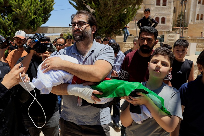Ayah dan saudara laki-laki Sam Abu Haykal, seorang bayi Palestina berusia 7 bulan yang dibunuh oleh tentara Israel, membawa jenazahnya selama pemakamannya di Hebron di Tepi Barat yang diduduki Israel, 6 Juni 2026. REUTERS/Mussa Qawasma