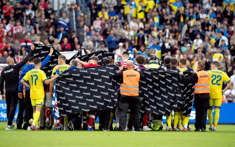 Para pemain dan staf Ukraina dan Denmark berkumpul setelah pertandingan dihentikan karena Christian Eriksen dari Denmark pingsan saat pertanidngan persahabatan di Stadion Stadion Odense, Denmark, Minggu (7/6/2026). (Bo Amstrup/Ritzau Scanpix via REUTERS)