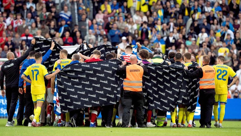 Para pemain dan staf melindungi Christian Eriksen dari Denmark saat ia meninggalkan lapangan untuk mendapatkan perawatan medis setelah pingsan saat pertanidngan persahabatan di Stadion Stadion Odense, Denmark, Minggu (7/6/2026). (Bo Amstrup/Ritzau Scanpix via REUTERS)