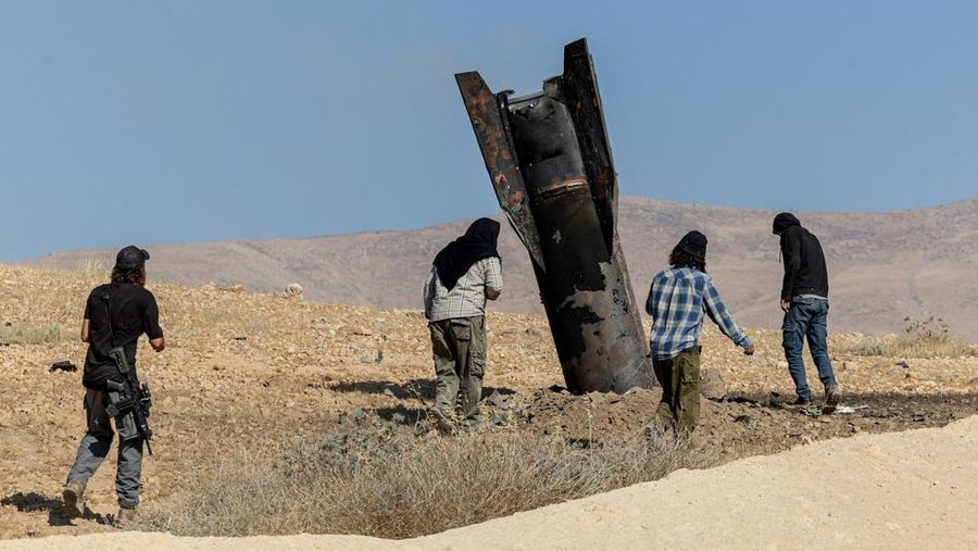 Para pemukim Israel berdiri di samping bagian rudal yang mencuat dari tanah, setelah serangan dari Iran, di Tepi Barat bagian tengah yang diduduki Israel, 8 Juni 2026.