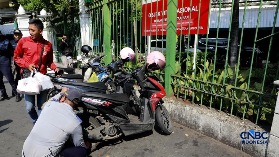Petugas Dinas Perhubungan (Dishub) DKI Jakarta saat menilang mobil taksi yang parkir sembarangan di kawasan Dukuh Atas, Jakarta, Senin (8/6/2026). (CNBC Indonesia/Muhammad Sabki)
