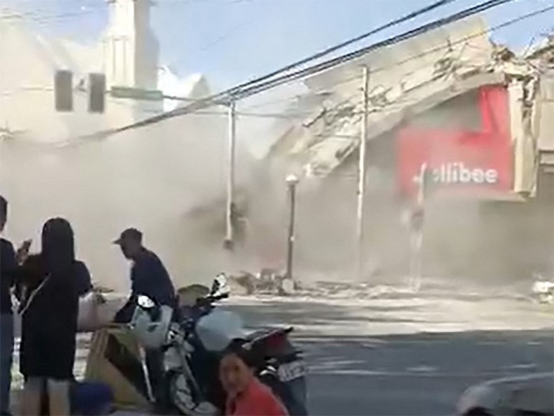 Polisi berkumpul di depan reruntuhan restoran cepat saji Jollibee setelah gempa bumi berkek magnitude 7,8 di Kota General Santos pada 8 Juni 2026. (AFP/EDWIN ESPEJO)