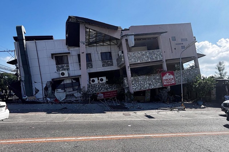 Polisi berkumpul di depan reruntuhan restoran cepat saji Jollibee setelah gempa bumi berkek magnitude 7,8 di Kota General Santos pada 8 Juni 2026. (AFP/EDWIN ESPEJO)