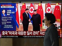 Seorang wanita berjalan melewati layar televisi yang menampilkan siaran berita dengan cuplikan arsip pertemuan tahun 2019 antara Presiden Tiongkok Xi Jinping dan pemimpin Korea Utara Kim Jong Un, di stasiun kereta api di Seoul, Korea Selatan, Senin (