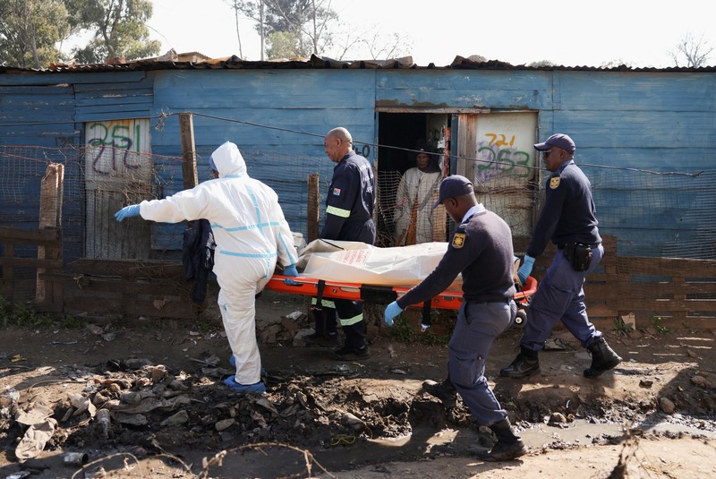 Seorang petugas polisi memberi isyarat di samping anggota tim forensik setelah, menurut polisi, seorang pria bersenjata melepaskan tembakan di permukiman kumuh di Cleveland, Johannesburg, Afrika Selatan, 10 Juni 2026. (REUTERS/Siphiwe Sibeko)