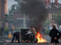Api berkobar selama protes setelah serangan pisau pada 8 Juni yang menyebabkan seorang pria terluka parah dan mendorong polisi untuk menyatakan insiden kritis, di Newtownards Road di Belfast, Irlandia Utara, 9 Juni 2026. (REUTERS/Isabel Infantes)