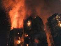 Thick smoke and flames rise as a major fire engulfs several apartment blocks at the Wang Fuk Court residential estate in Hong Kong's Tai Po district on November 26, 2025. At least four people were killed when a fire engulfed several high-rise blocks
