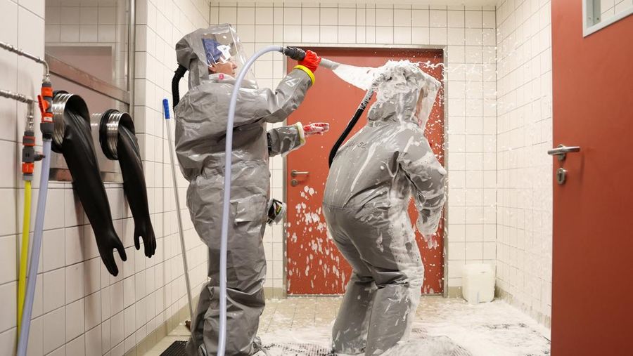 Para petugas kesehatan dari klinik Virchow di Berlin yang mengenakan perlengkapan pelindung lengkap menjalani dekontaminasi akhir sebelum keluar dari ruang isolasi Ebola saat institut tersebut memberikan tur melalui stasiun isolasi untuk pasien Ebola di Berlin, Jerman, 9 Juni 2026.