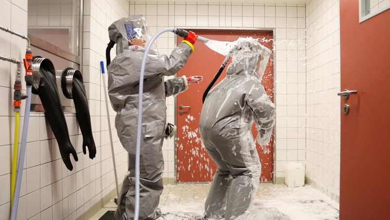 Para petugas kesehatan dari klinik Virchow di Berlin yang mengenakan perlengkapan pelindung lengkap menjalani dekontaminasi akhir sebelum keluar dari ruang isolasi Ebola saat institut tersebut memberikan tur melalui stasiun isolasi untuk pasien Ebola di Berlin, Jerman, 9 Juni 2026.